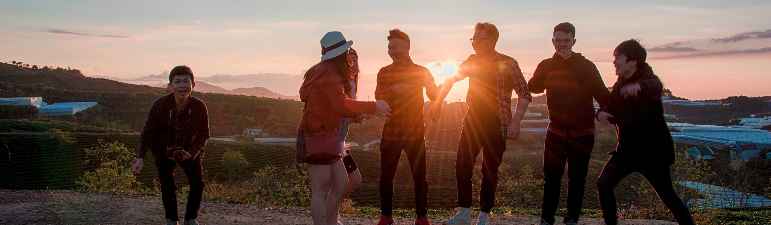 A group of teens laughing at sunset outside in nature.
